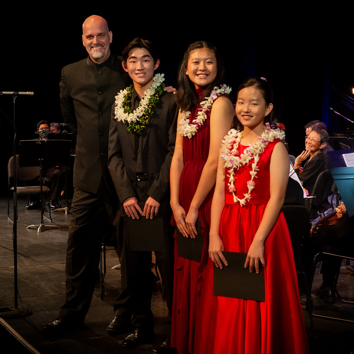 The 2023-24 Madeline Schatz-Harris Youth Concerto Competition winners with Kamuela Philharmonic conducter and artistic director Brian Dollinger on stage at Kahilu Theatre